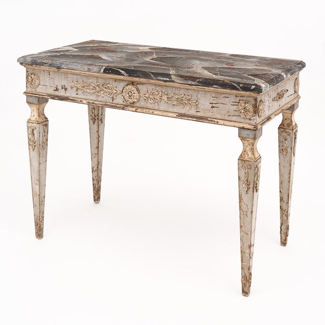 Pair of consoles from Italy featuring hand-carved floral friezes and tapered legs. The bases of the tables have a soft...