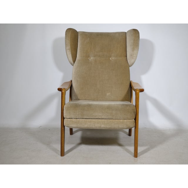 Vintage wingback chair with a folding mechanism from the 1970s. High backrest with side wing panels, solid wood frame, and...