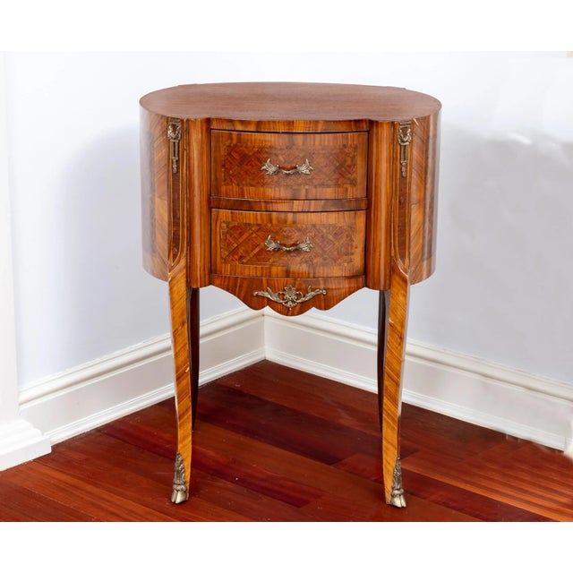A bowed front with center double drawers decorated with parquet inlay and original brass pulls supported by a scalloped...