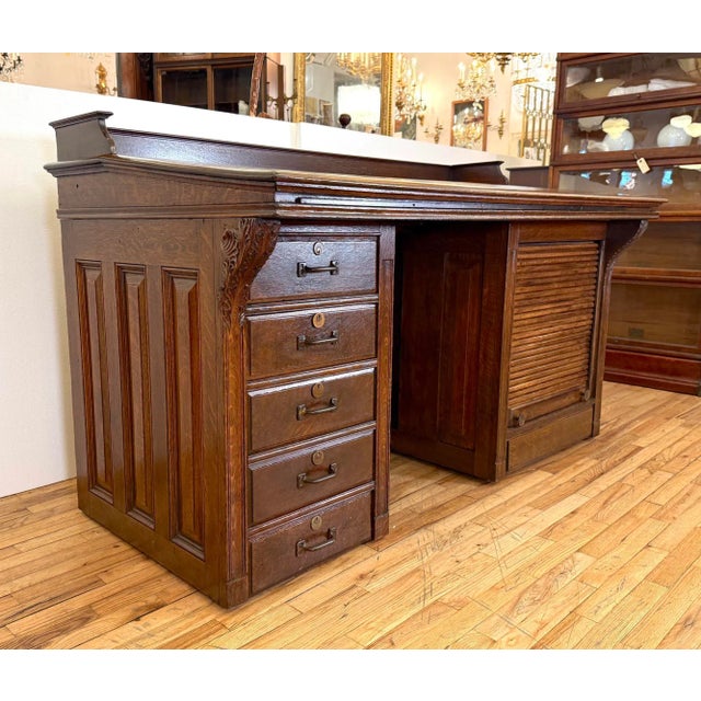 Antique clerk's desk made of quarter sawn oak in a dark finish and intricately carve corbels on each side. It features...