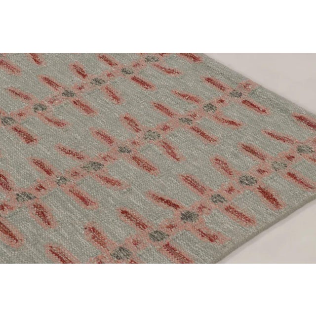 Handwoven in wool and natural yarns, this 9x12 Scandinavian rug has a soft sage field with delicate coral geometric...