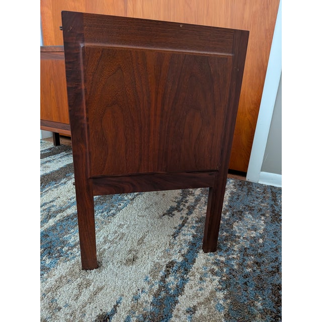 A pair of mid-century modern furniture pieces are walnut and slate-top nightstands Attributed to Jack Cartwright for...