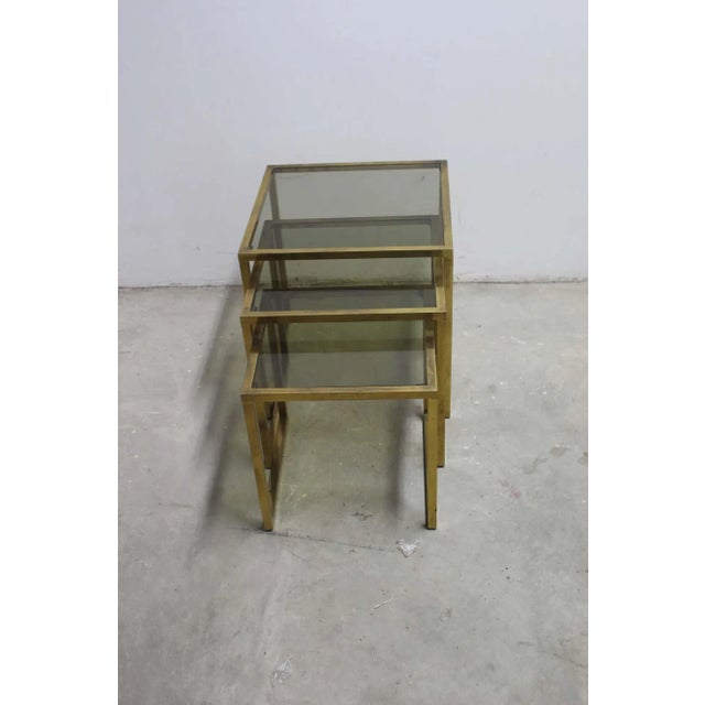 Mid century set of three nesting tables. Vintage brass base with the fume glass top. Brass is not polish but shows...