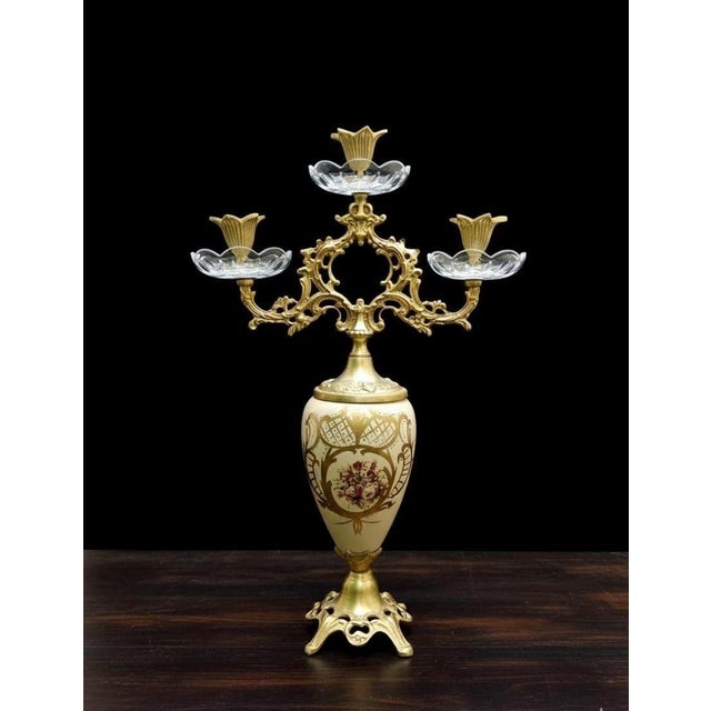 DIMENSIONS Height: 19 inches This luxurious three-arm candle holder showcases elaborate scrollwork inspired by classic...