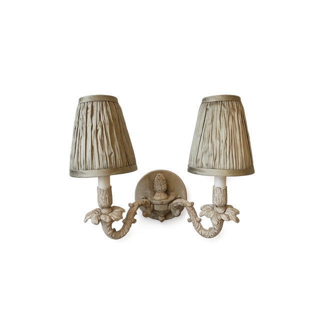 Pair of Currey & Company double-arm wall sconces. Beautiful vintage-inspired design with carved detail and a soft, aged...