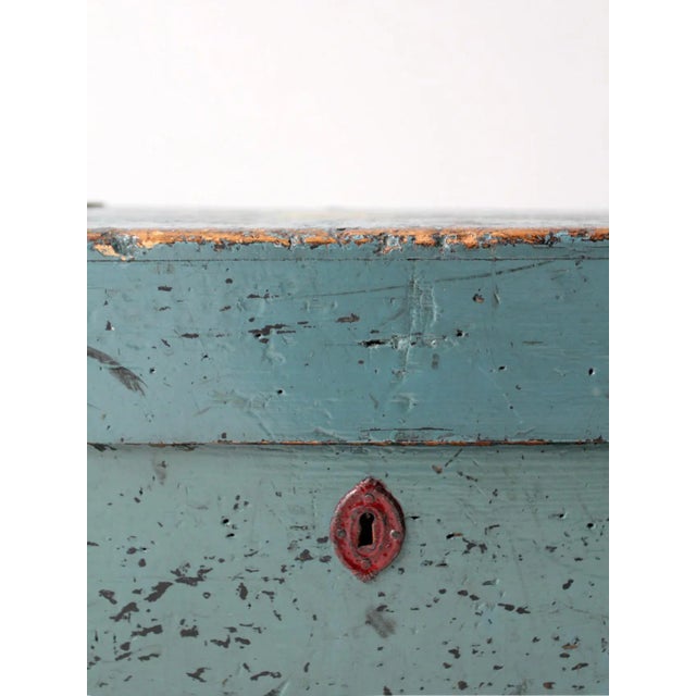 This is an antique wooden trunk. The charming hand-painted sky blue wood trunk features red metal trim and handles with...