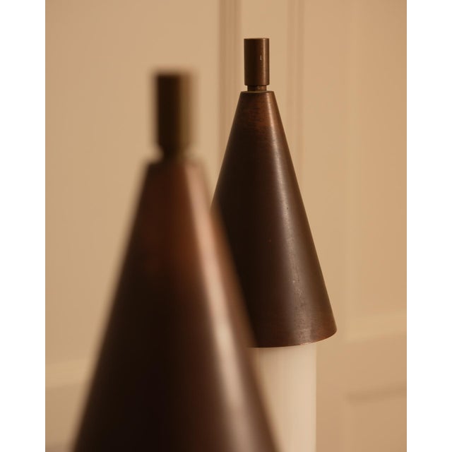 A striking pair of vintage italian wall sconces, circa 1970s, in dark brown metal and opaque white glass. featuring...