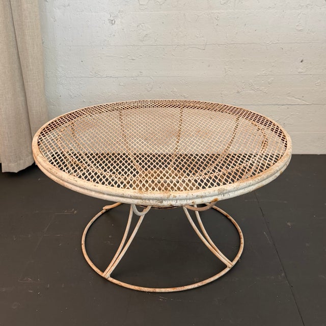 This classic Mid-Century Modern outdoor coffee table showcases a sculpted wire-hoop pedestal base supporting a signature...