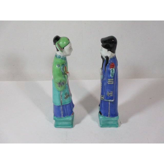 A vintage pair of Chinese male and female porcelain figurines, dressed in period robs. They are hand painted in colors of...