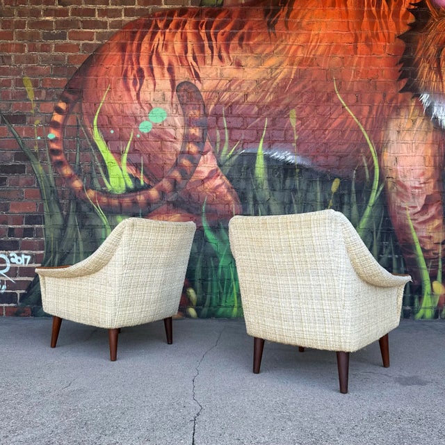 This is a pair of vintage Danish modern lounge chairs. They feature swooping arms topped off by nice walnut armrests...
