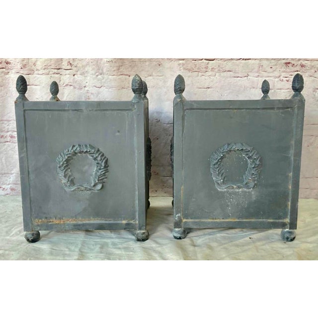 Pair of Neoclassical Metal Planters With a Wreath Motif. Pair of American Neoclassical style planters features grey...
