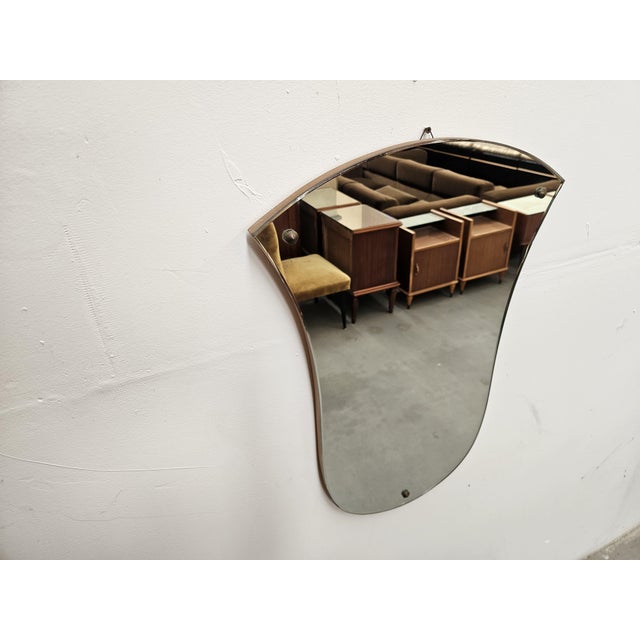 Vintage 1960s mirror with a wooden frame and exposed mirrored glass. It has a small hook on the back for hanging on the wall.