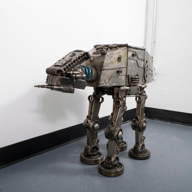Large metal sculpture composed of various welded metal parts and tools inspired by Star Wars AT-AT Imperial walker.