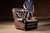 Classic English club chair upholstered in dark brown leather with a deeply button-tufted back, rolled arms, and oversized...