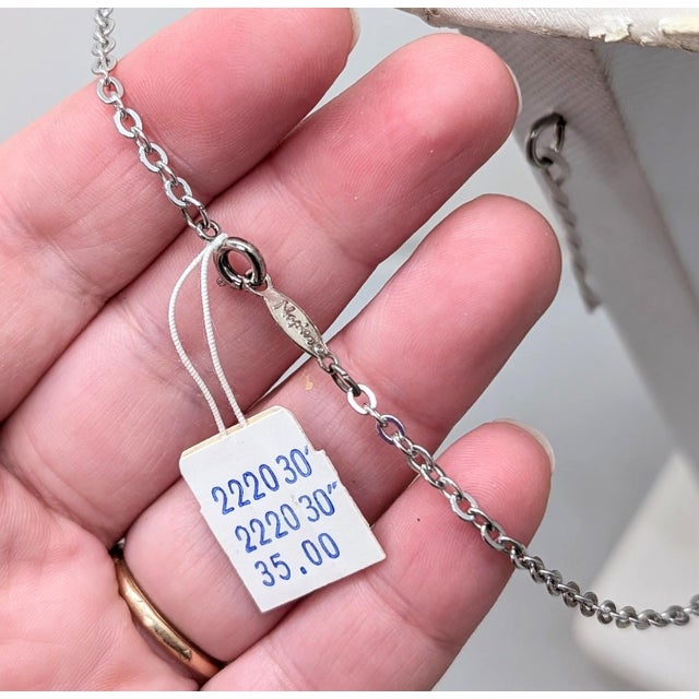 Rhodium plated feathers charm long necklace with spring ring clasp. Marked "Napier" in script on a plaque that the spring...