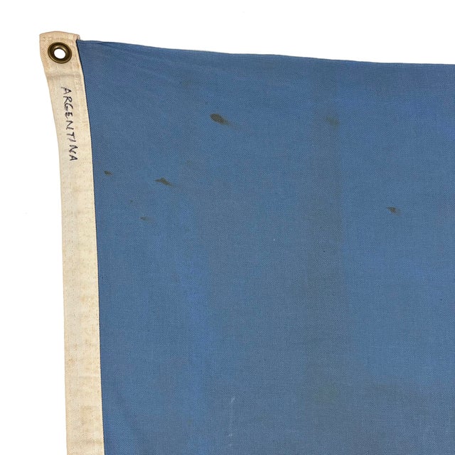 This vintage Argentine flag is made from a cotton cloth, with blue panels sewn in place, and printed emblem visible on...