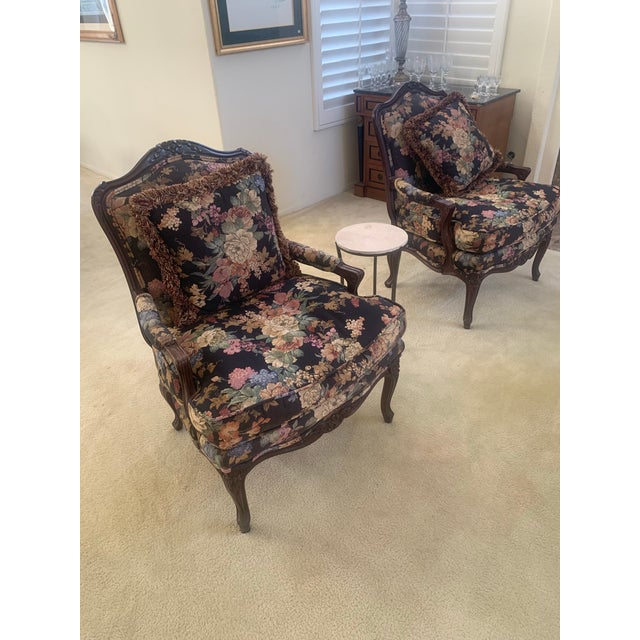 Beautiful pair of vintage upholstered armchairs featuring a rich dark floral tapestry fabric and carved wood detailed...