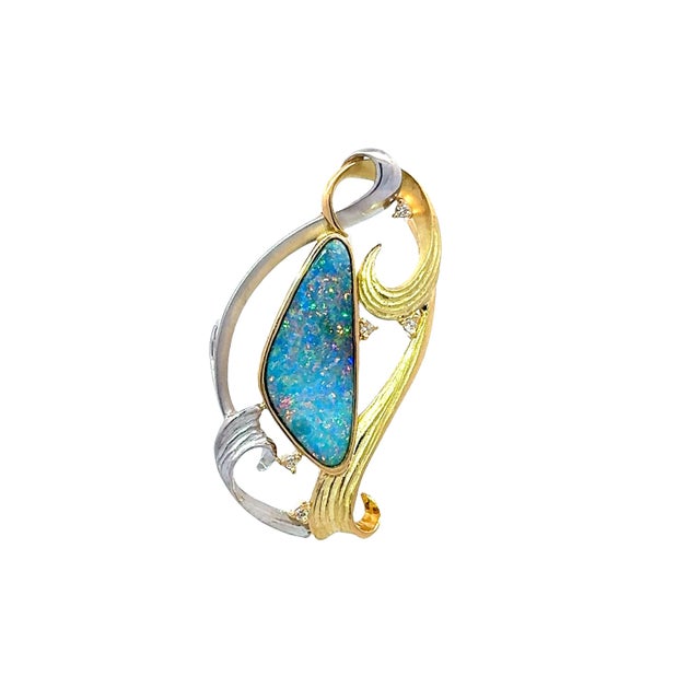 A contemporary brooch-pendant showcasing an elegant design with a striking opal centerpiece. The opal displays a...