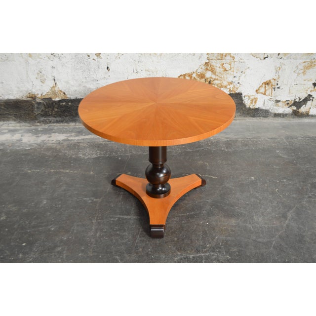 Bookmatched golden elm top on solid dark flame birch pedestal tripod base.