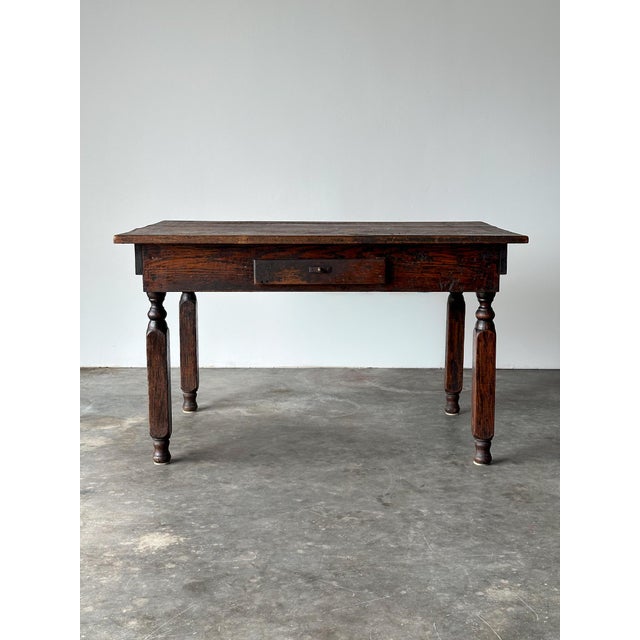 This country store table is constructed of solid oak, with turned baluster legs, canted chamfered corner blocks, and a...