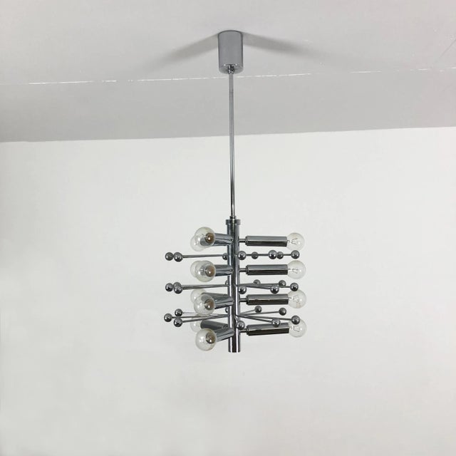 This pendant lamp in the style of Cosack is made of solid metal, finished in a chrome tone. The piece features twelve...