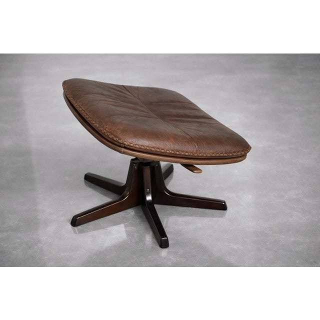 This vintage armchair with footstoolwas produced by the Danish manufacturer Berg Furniture during the 1970s. The furniture...