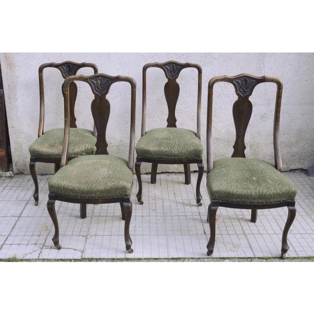 Group of four oak chairs with arched backrest and carved on the high central part, upholstered seat and worked and armed...