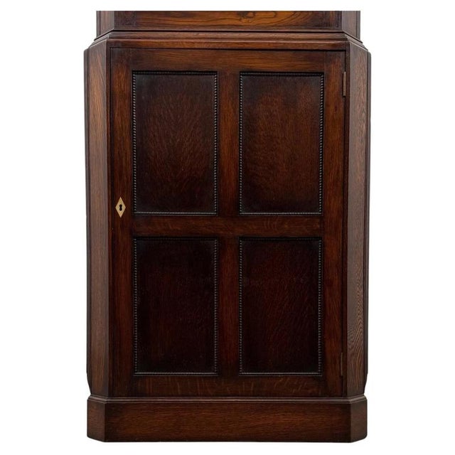 A handsome English Edwardian corner cabinet dating from the early 20th century, finely constructed in oak and designed to...