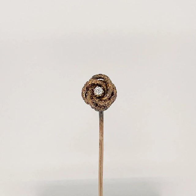 A fine antique Edwardian gold and diamond love knot stickpin. In 10k gold. Set with a round white diamond to the center of...