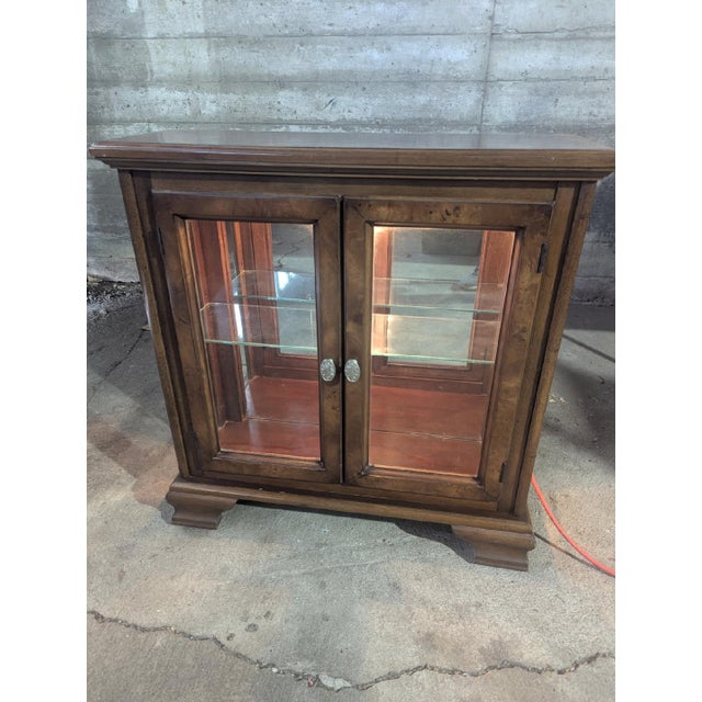 Vintage Curio/Console Cabinet has an rich wood Finish. The Cabinet has Two Doors with One Glass Shelf, a Mirrored Back,...