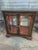 Vintage Curio/Console Cabinet has an rich wood Finish. The Cabinet has Two Doors with One Glass Shelf, a Mirrored Back,...