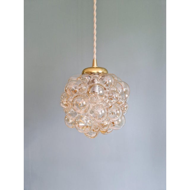 Trio of amber-colored bubble glass and brass pendant lights, designed by helena tynell for the german manufacturer...