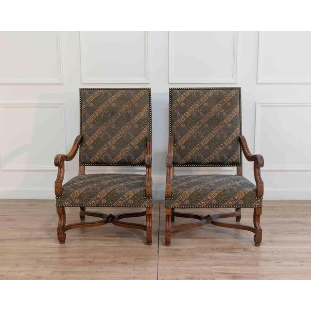 A refined pair of French armchairs crafted in solid walnut, dating to the turn of the 20th century. These chairs feature...