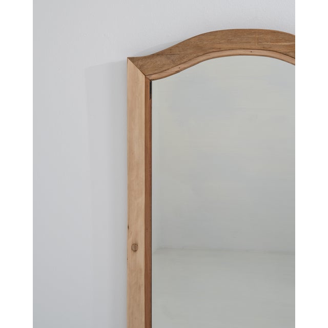 A simple yet elegant wall mirror featuring a wooden frame with natural patina that highlights its age and authenticity....