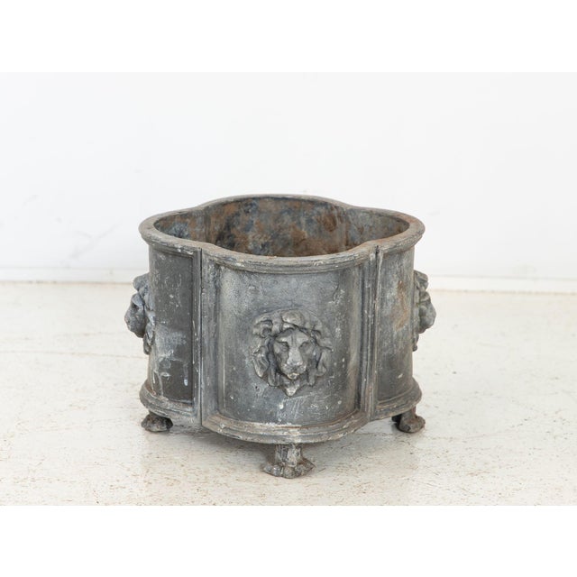 This 1850s antique English lead planter or cachepot features a quatrefoil form with lion-head reliefs and lion-paw feet...
