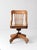An early 20th century Spitzers office chair with a sculpted wood frame, slatted back, and shaped seat set above its...