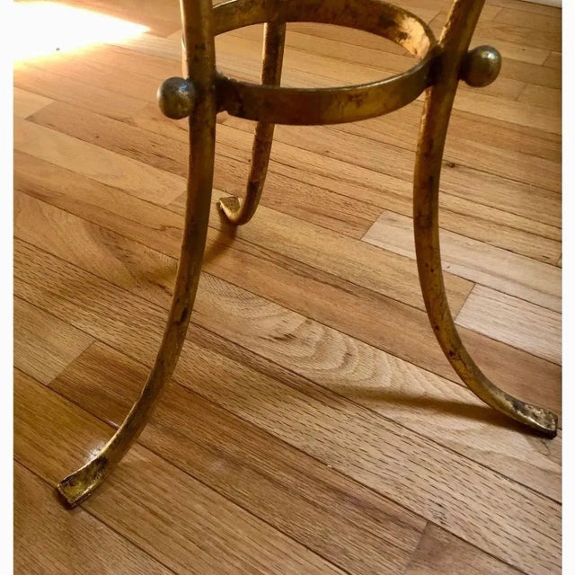 Offered is a vintage regency style accent table. This piece features a thick round piece of glass set atop a gold painted...