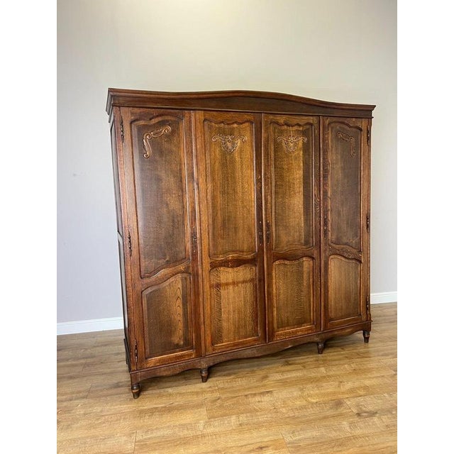 An elegant Vintage French Louis wardrobe crafted from Oak, featuring four panelled doors, decorative carved detailing, a...