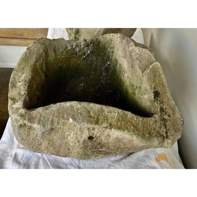 A sculptural pair of hand-carved stone planters, each hewn from solid natural stone and showcasing beautifully irregular,...