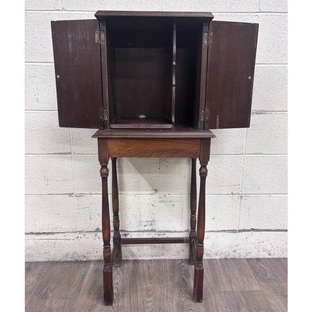 This is a gorgeous antique Tudor Revival walnut silver, jewelry, or collector cabinet circa 1920, featuring figured...