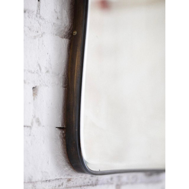 A scroll shaped mid century Italian brass framed mirror. Thick glass with a beveled edge shows off the Italian...