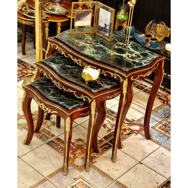 Elegant Rococo style nesting tables featuring a luxurious set of three accent tables topped with sophisticated black...