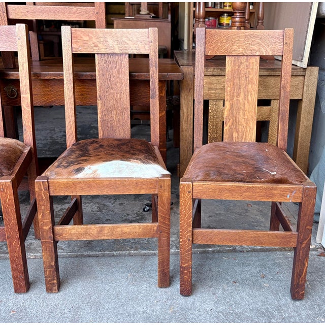 Finish is older or original and each chair has a unique natural cowhide upholstered seat featuring varying patterns of...