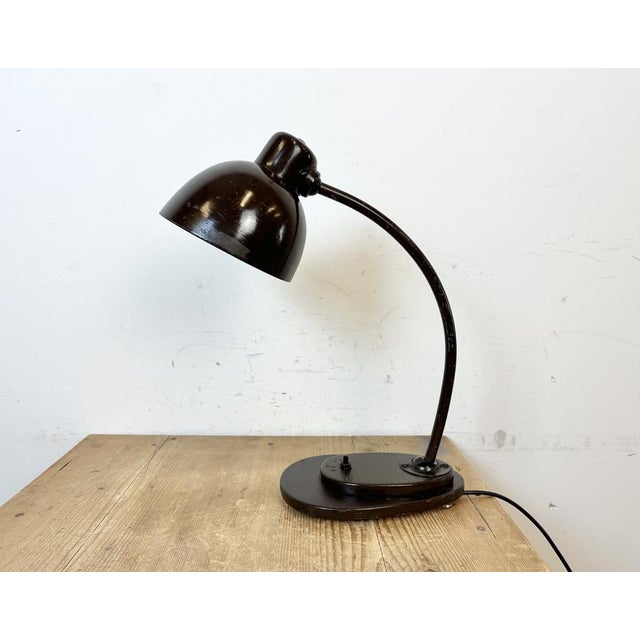 This dark brown industrial desk lamp was made in former Czechoslovakia during the 1960s. The lamp has an aluminium shade,...