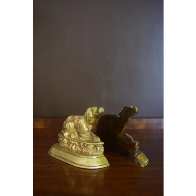 A charming pair of early 20th-century cast brass bookends depicting reclining spaniels — loyal and watchful, frozen mid-...
