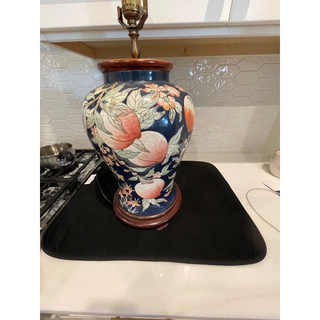 Vintage Chinese bulbous table lamp. The lamps has a wooden base and top. The colors are navy blue, peach and a light...