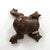 A low frog-form footstool in mottled brown leather, the rounded body formed from shaped stitched panels with a long hand-...
