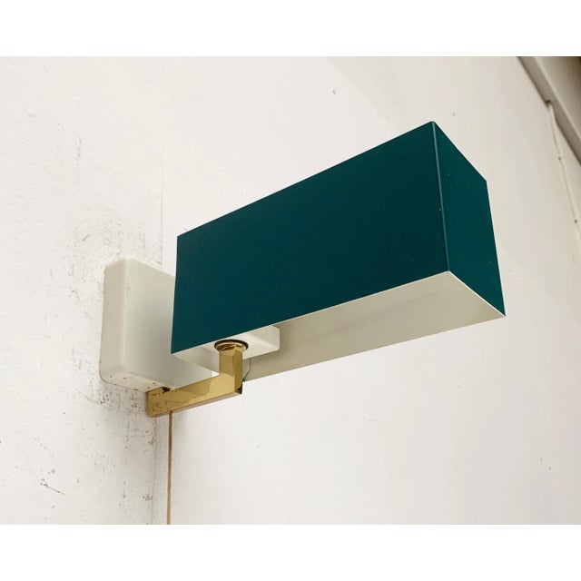 Simple Mid Century wall light by Kaiser lights. A minimalist design. At the end of a angled arm sits a simple, rectangular...