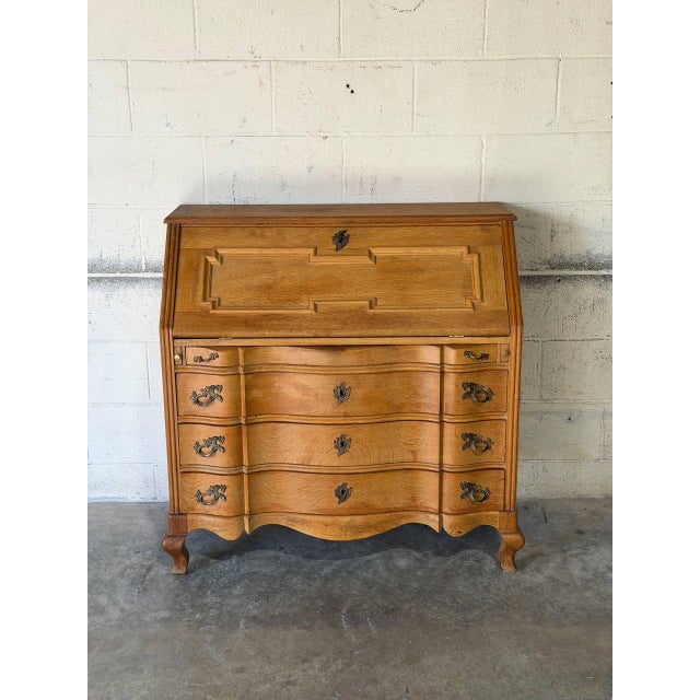 This bureau features a drop-front desk that opens to reveal an interior with small drawers and a central cubby. The lower...