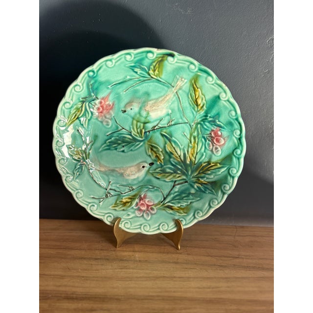 Barbotine majolica plate molded in relief with two birds on leafy branches among pink blossoms, within a molded wave-...